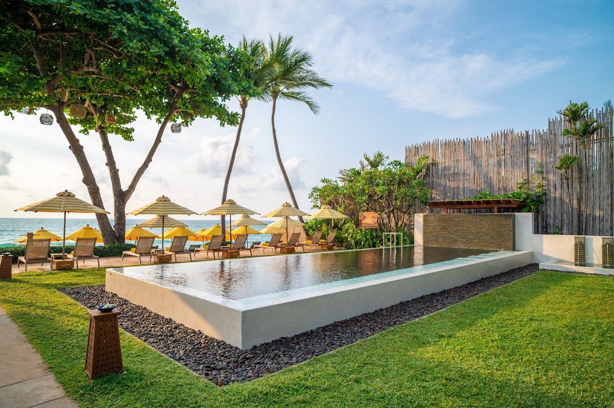 Buri Rasa Village Samui — the resort's infinity pool with yellow sun umbrellas and direct Chaweng Beach access beyond