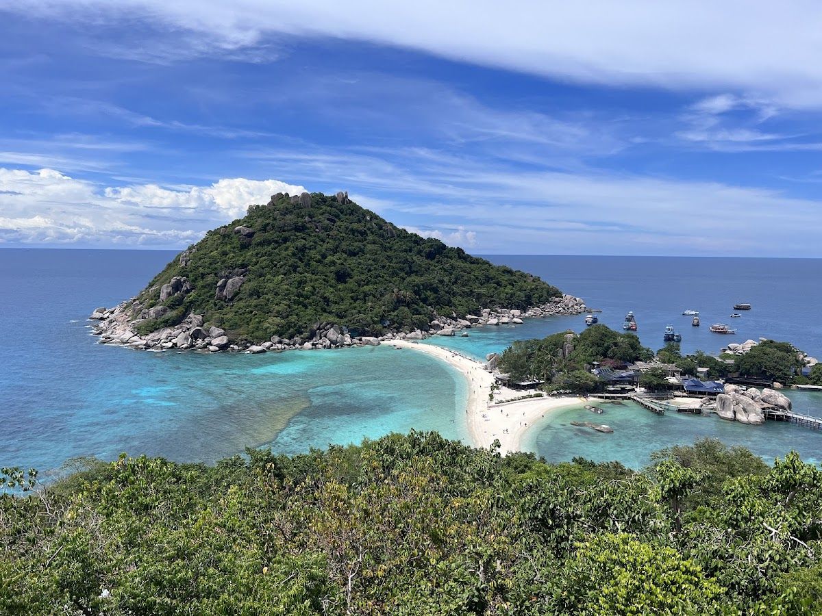 View from the Koh Nang Yuan viewpoint looking down at the sandbar connecting three islands, with turquoise gulf water and Koh Tao in the background