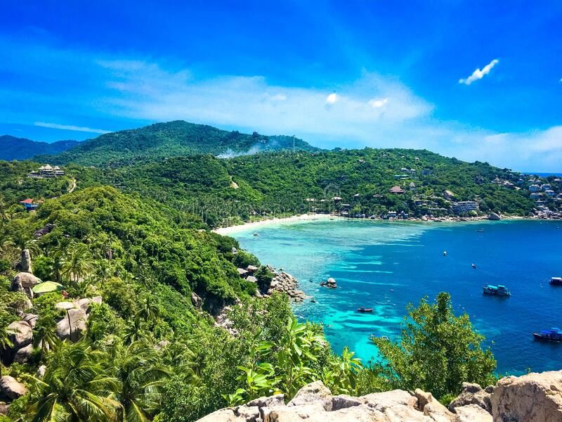 Koh Tao island seen from the water, with turquoise gulf and tree-lined hills rising from the shore