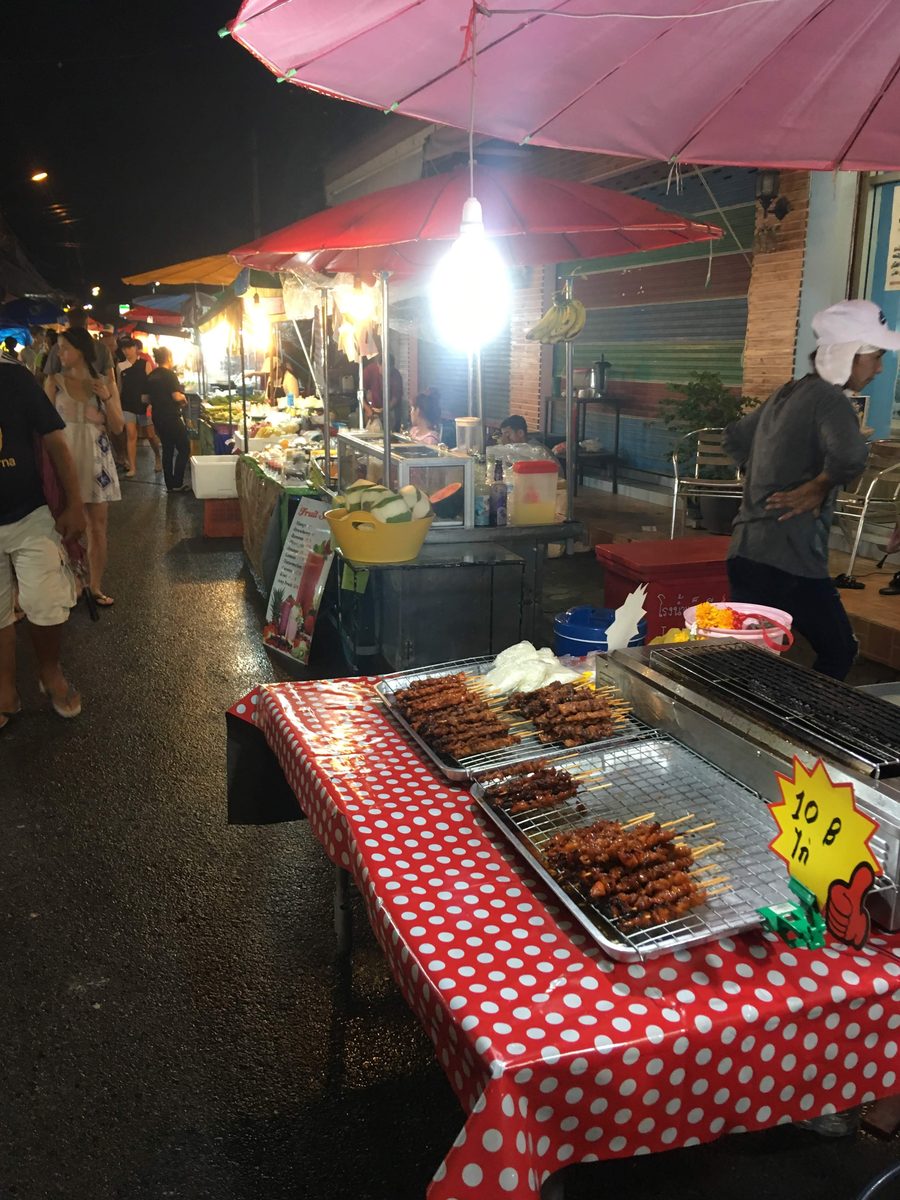 Food stalls at Lamai Sunday Night Market on Koh Samui, with grilled pork skewers priced at 10 baht each under a red umbrella