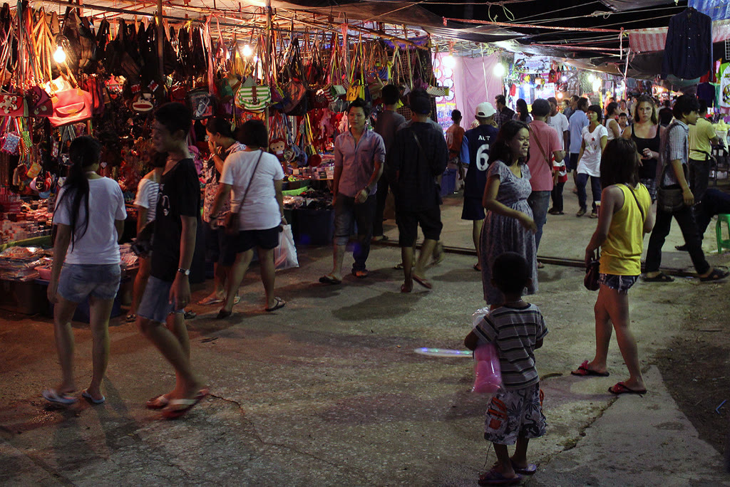 A Koh Samui night-market food stall in 2012. The file does not name the market. Friday's walking street is Fisherman's Village in Bophut. Photo: Per Meistrup, Wikimedia Commons, CC BY-SA 4.0. A night food stall on Koh Samui, with a cook working over a steel counter under warm lights