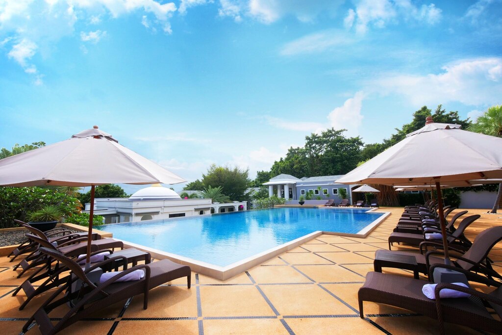Pool at Absolute Sanctuary with white umbrellas, wooden loungers and a view over the water