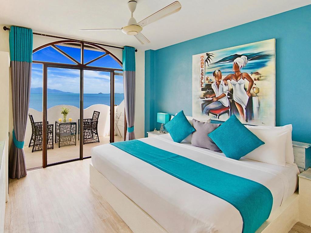 Bedroom at Hacienda Fisherman's Village with a dark wood bed, white linens and a balcony toward the sea